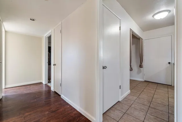 a view of a hallway with wooden floor and a bathroom