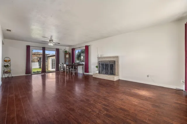 an empty room with wooden floor fireplace and windows