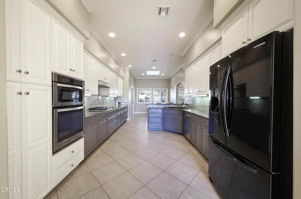 a large kitchen with a large stainless steel appliances kitchen island granite countertop a refrigerator and a sink