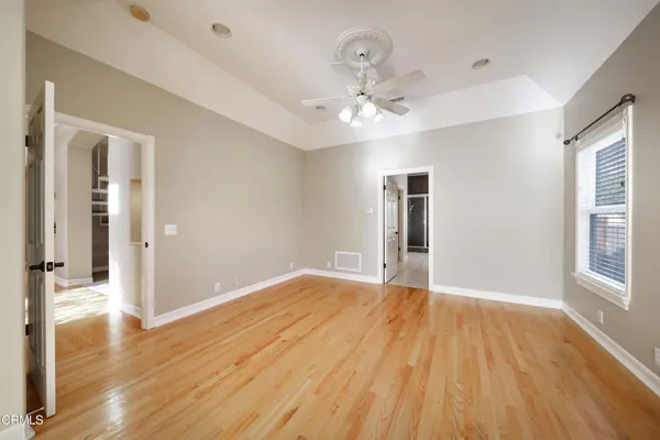 a view of an empty room with wooden floor and a window