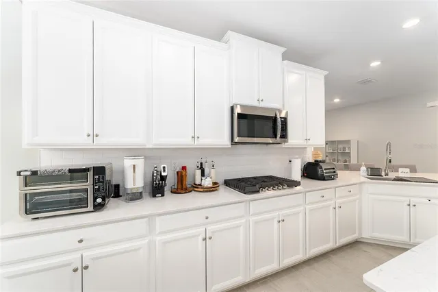 a kitchen that has a lot of cabinets in it with appliances and cabinets