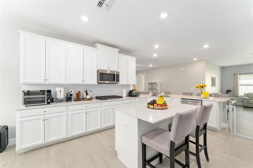 1244 Southeast 42nd Road Ocala, FL 34480 - Photo 25 of 56 a kitchen with stainless steel appliances granite countertop a sink a stove a dining table and chairs with white cabinets