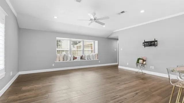 an empty room with wooden floor and windows