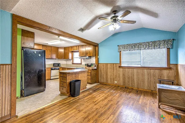 a kitchen with stainless steel appliances kitchen island granite countertop a refrigerator a stove and a wooden floors