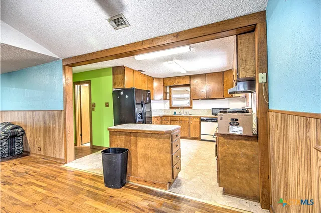 a kitchen with a refrigerator and a wooden cabinets