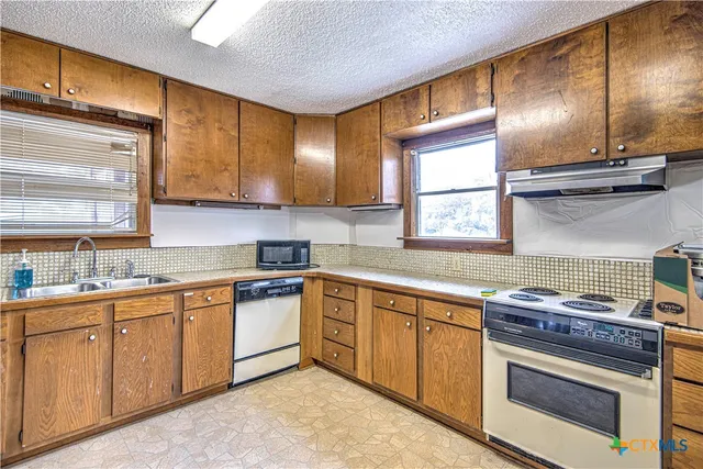a kitchen with granite countertop stainless steel appliances sink cabinets and window