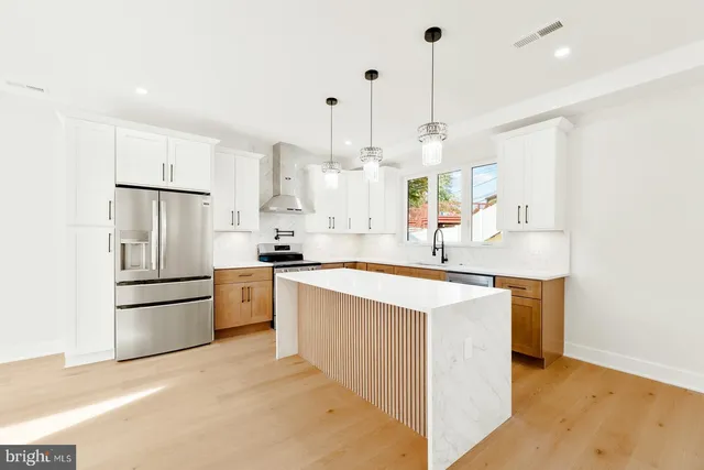 a kitchen with stainless steel appliances kitchen island granite countertop a sink stove and refrigerator