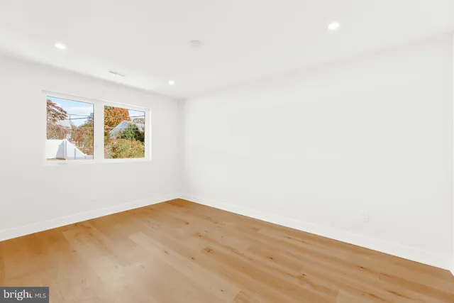 an empty room with wooden floor and window