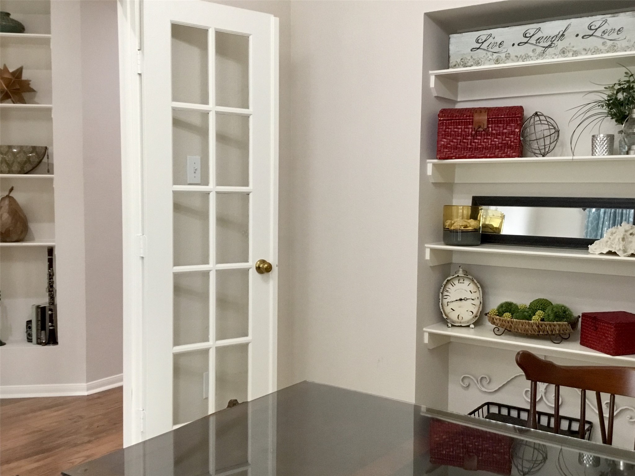 3 North Spiral Vine Circle Spring, TX 77381 - Photo 28 of 41 This photo showcases a cozy room with a glass-panel door leading to another space. Built-in shelves display decorative items, including a clock and plants. The room features light-colored walls and a wooden floor, creating a warm and inviting atmosphere.