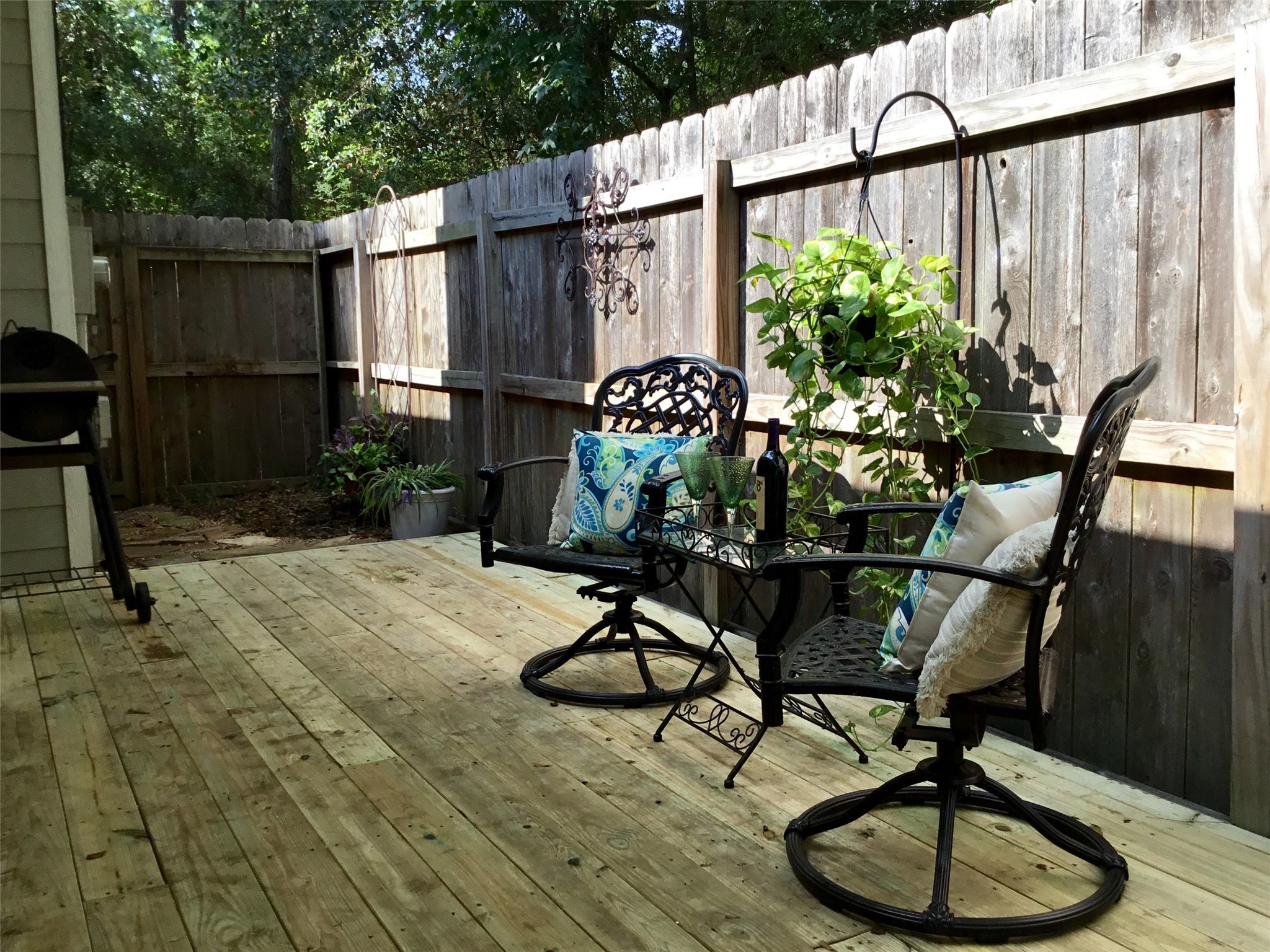 3 North Spiral Vine Circle Spring, TX 77381 - Photo 37 of 41 This photo showcases a cozy wooden deck with decorative iron furniture, including two chairs and a small table. The space is enhanced by lush greenery and privacy fencing, making it perfect for relaxing or entertaining outdoors.