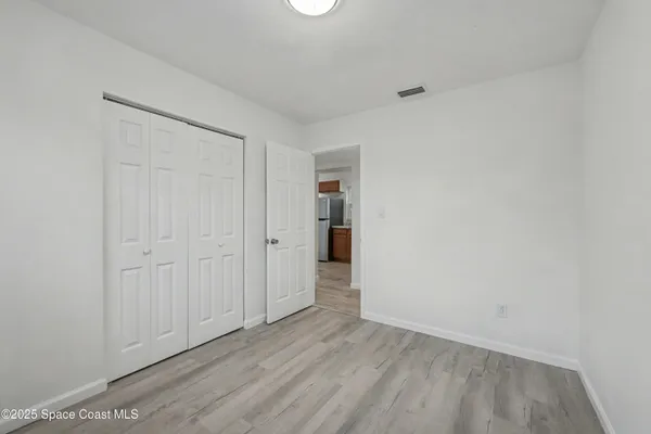 a view of a hallway with wooden floor and closet