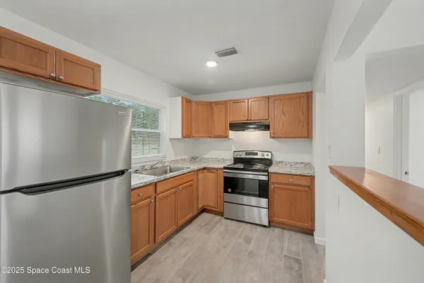 a view of a kitchen with wooden floor and windows