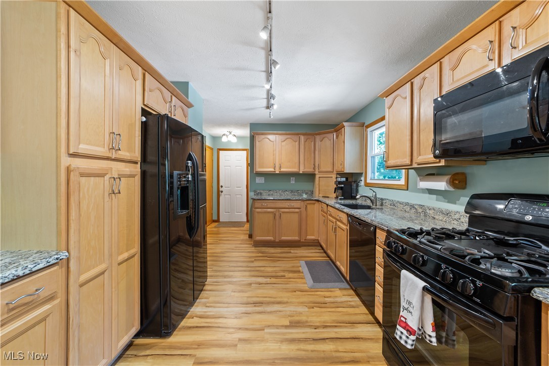 3694 Nichols Road Medina, OH 44256 - Photo 6 of 47 Kitchen with black appliances, light stone countertops, light wood-style floors, light brown cabinets, and rail lighting