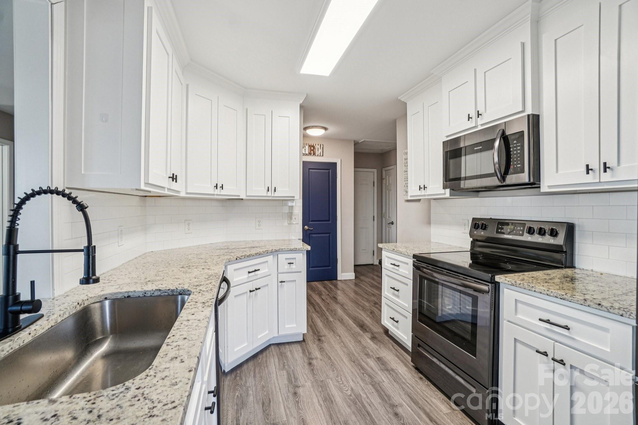 178 Rowe Court Hendersonville, NC 28792 - Photo 7 of 21 a kitchen with granite countertop a stove a sink and a microwave