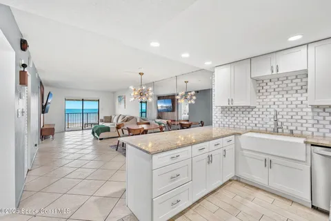 a large white kitchen with a stove a sink a window and white cabinets