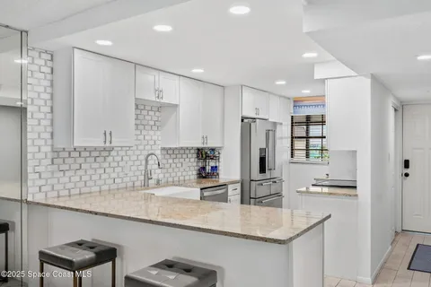 a kitchen with stainless steel appliances granite countertop a sink refrigerator and cabinets