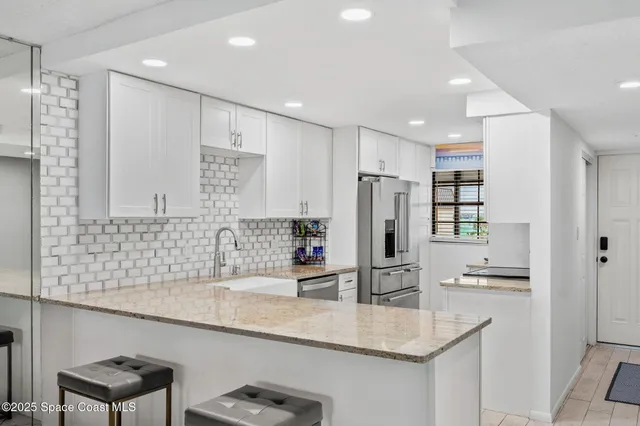 a kitchen with stainless steel appliances granite countertop a sink refrigerator and cabinets