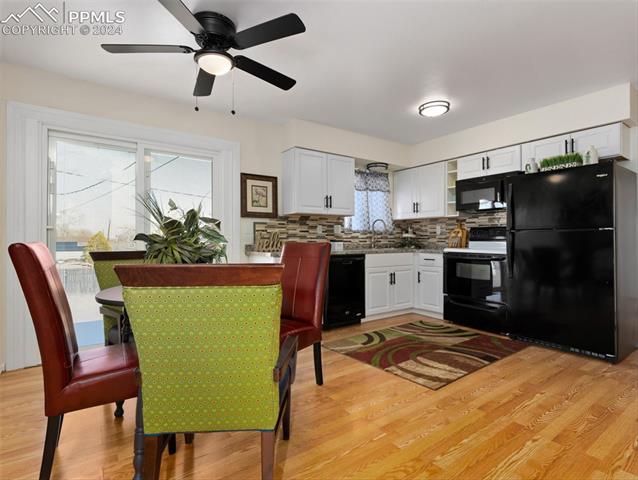 142 Mac Neil Road Pueblo, CO 81001 - Photo 10 of 24 Kitchen with white cabinets, black appliances, and light hardwood / wood-style floors