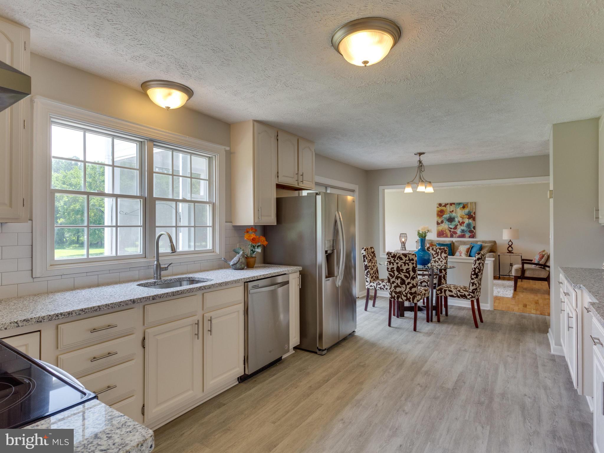11617 Stuart Mill Road Oakton, VA 22124 - Photo 8 of 30 a kitchen with stainless steel appliances granite countertop a stove top oven a sink dishwasher a dining table and chairs with wooden floor