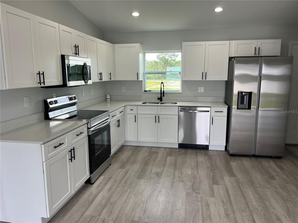 7209 Ancha Street Sebring, FL 33872 - Photo 3 of 20 a kitchen with stainless steel appliances a sink dishwasher a refrigerator and a stove with wooden floors