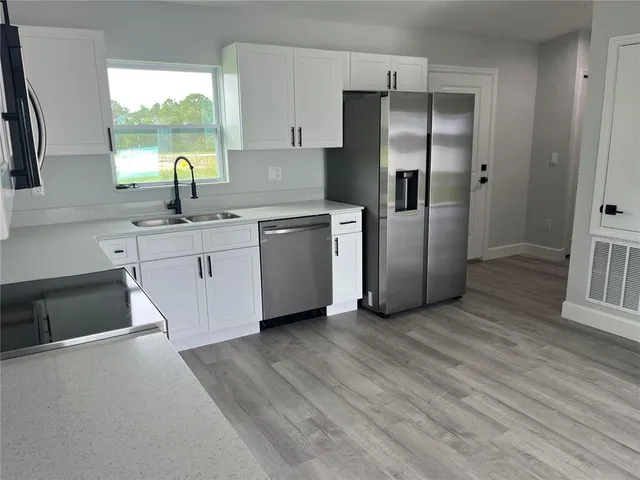 a kitchen with stainless steel appliances granite countertop a refrigerator a sink and a stove