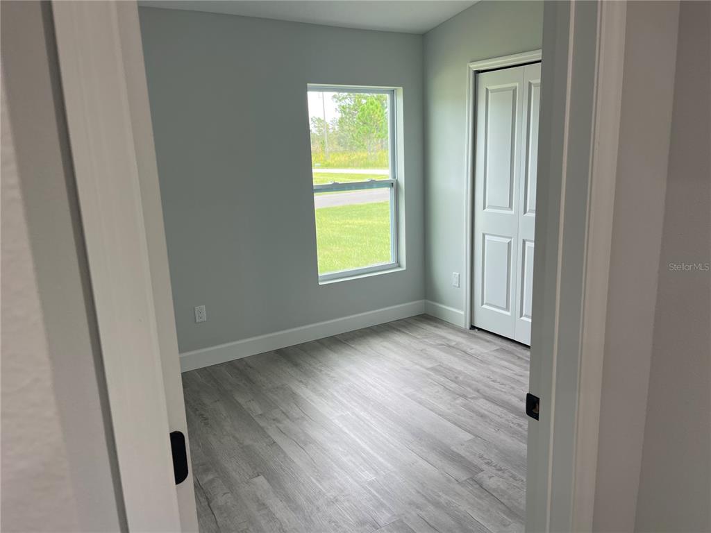 7209 Ancha Street Sebring, FL 33872 - Photo 8 of 20 a view of an empty room with wooden floor and a window