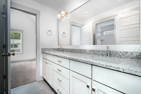 a bathroom with a granite countertop sink mirror and cabinets
