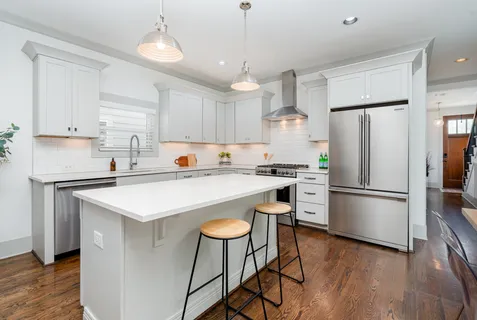 a kitchen with stainless steel appliances a refrigerator a stove a sink dishwasher and a refrigerator with wooden floor