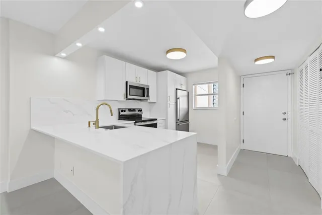 a view of a kitchen with a sink dishwasher a refrigerator and cabinets