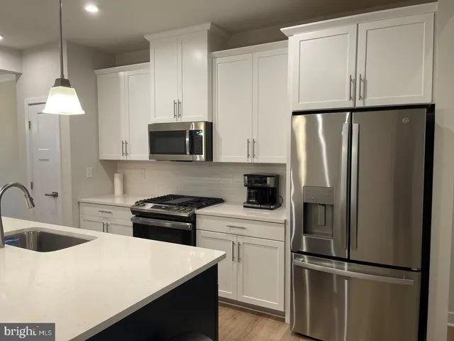 a kitchen with a refrigerator a stove a sink and white cabinets