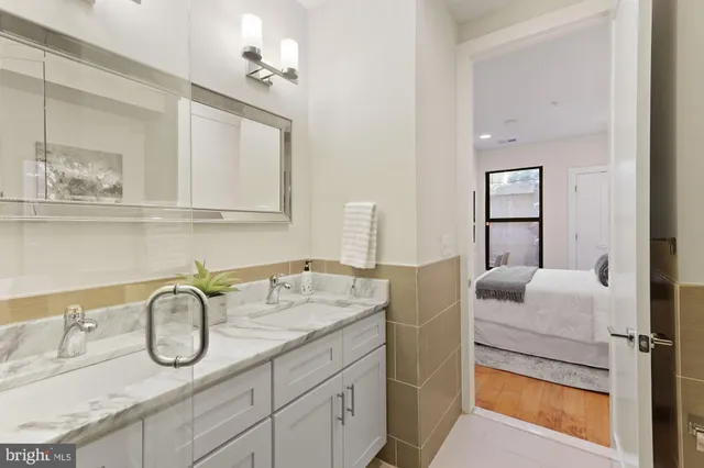 a en suite bathroom with a granite countertop double vanity sink and mirror
