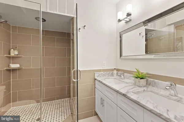 a bathroom with a granite countertop sink a mirror and a shower