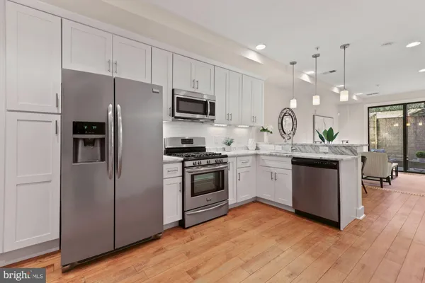 a kitchen with kitchen island granite countertop a refrigerator oven a sink dishwasher and white cabinets with wooden floor