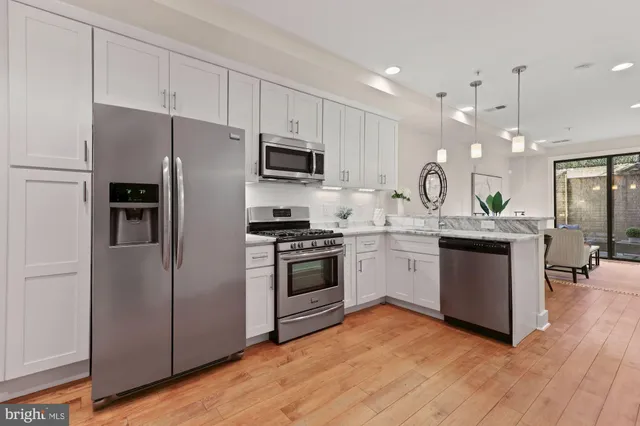 a kitchen with kitchen island granite countertop a refrigerator oven a sink dishwasher and white cabinets with wooden floor