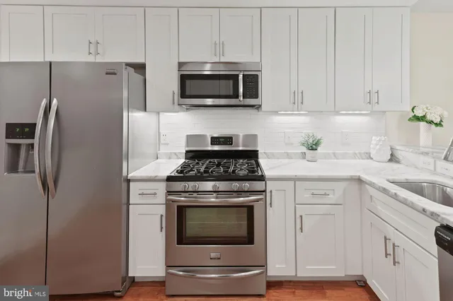 a kitchen with stainless steel appliances white cabinets a stove a sink and a refrigerator