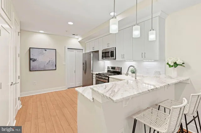 a very nice looking dining room with kitchen island white cabinets and wooden floor