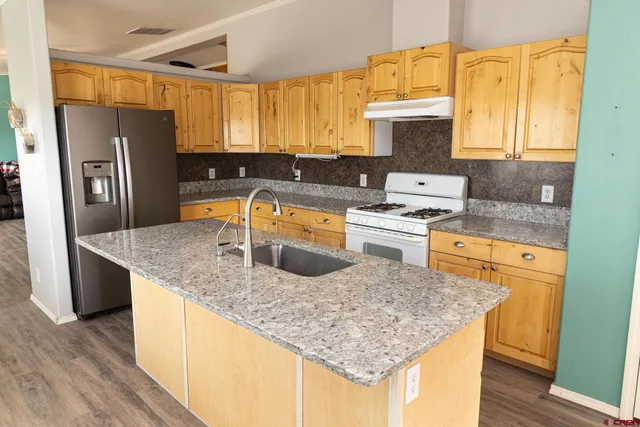 a kitchen with stainless steel appliances granite countertop a sink a microwave refrigerator and stove