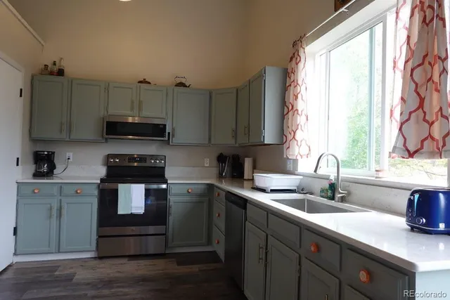 a kitchen with stainless steel appliances a sink a stove a microwave a sink and cabinets