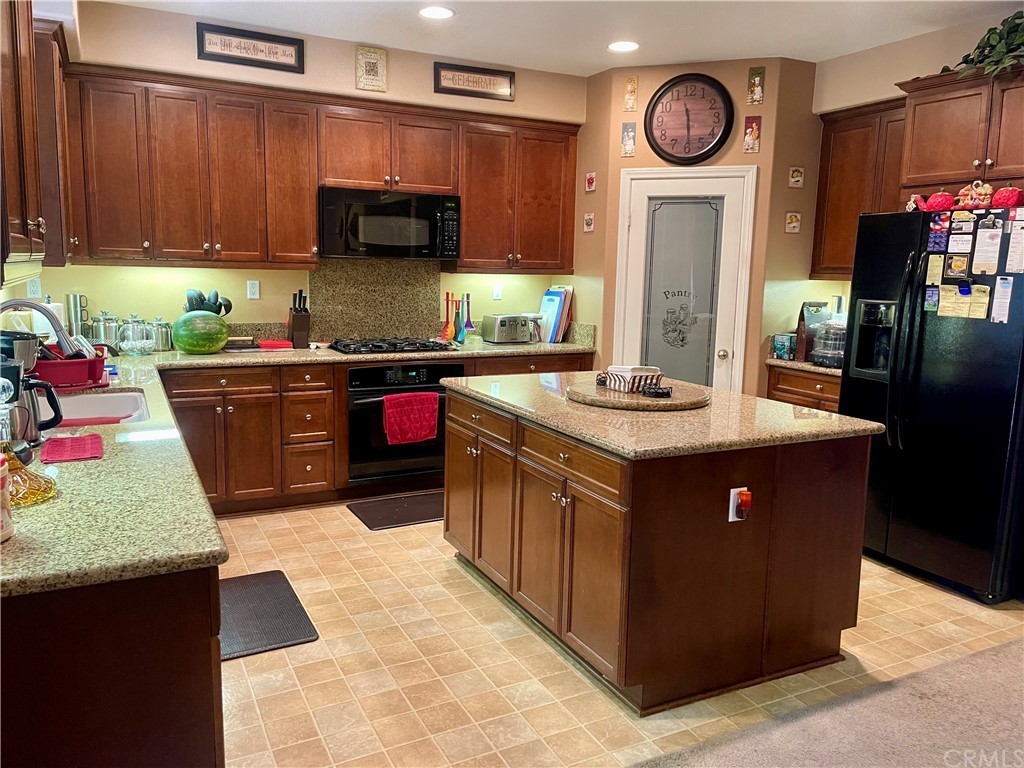 29839 Winter Hawk Road Menifee, CA 92586 - Photo 4 of 21 a kitchen with stainless steel appliances granite countertop a stove a refrigerator a sink and dishwasher with wooden cabinets
