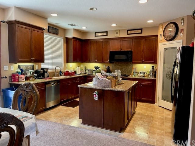 29839 Winter Hawk Road Menifee, CA 92586 - Photo 5 of 21 a kitchen with kitchen island granite countertop a sink dishwasher stove and refrigerator with wooden cabinets