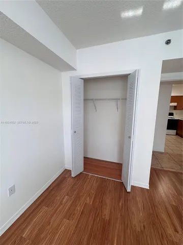 an empty room with wooden floor & closet and windows
