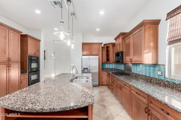 a kitchen with stainless steel appliances kitchen island granite countertop a sink refrigerator and cabinets
