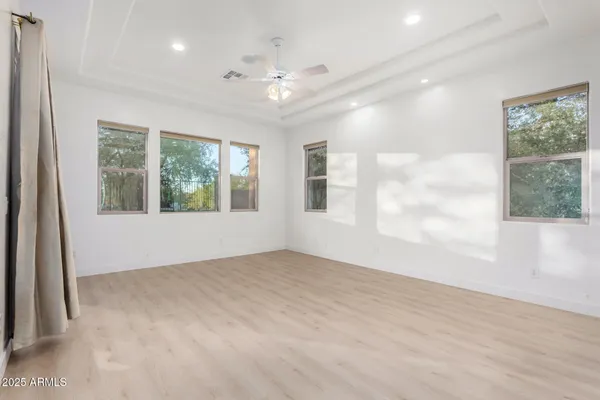 an empty room with windows and chandelier fan