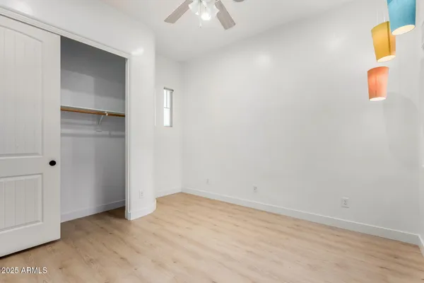 an empty room with wooden floor ceiling fan and windows