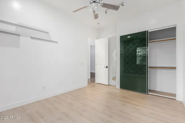 an empty room with closet and a chandelier fan