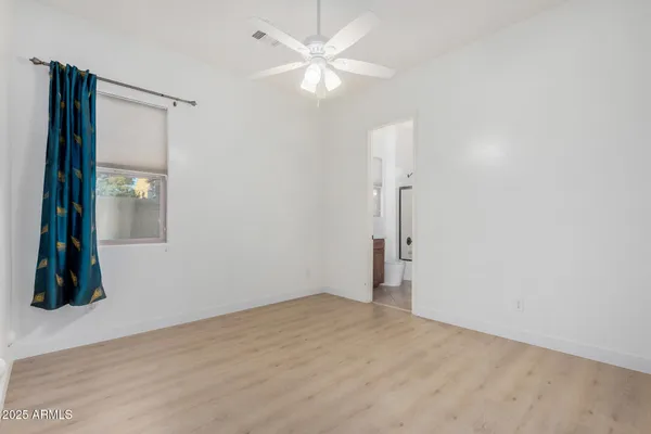 an empty room with wooden floor closet and fan