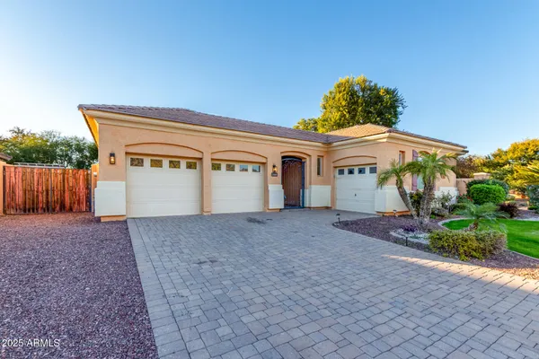 a view of a white house with a small yard and wooden fence