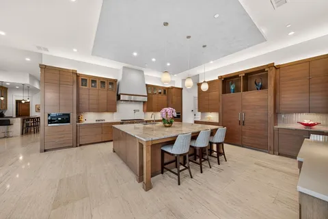 a kitchen with stainless steel appliances kitchen island granite countertop a table chairs sink and cabinets