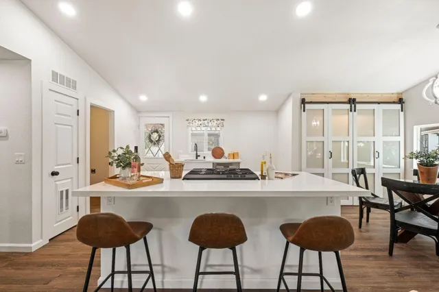 a kitchen with stainless steel appliances a dining table chairs and a large window
