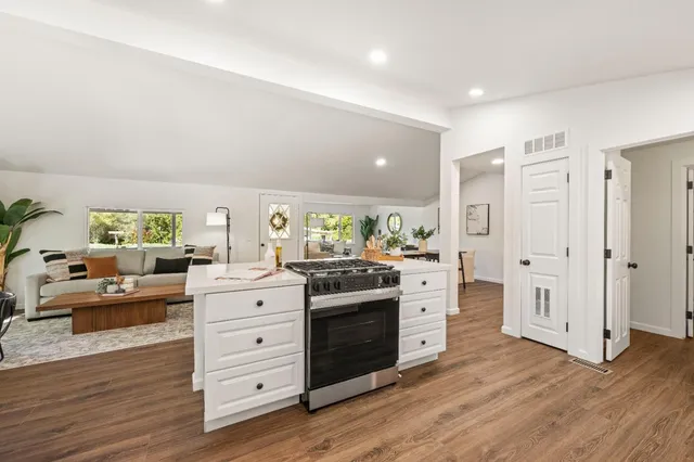 a kitchen with stainless steel appliances granite countertop a stove and wooden floor
